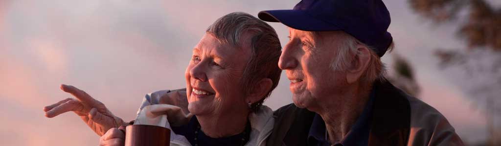 Happy senior couple watching sunset.