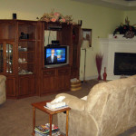 Living room at West Linn care home showing couches, corner fireplace, and entertainment center with TV