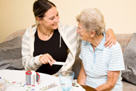 Nurse dispensing medication to elderly woman